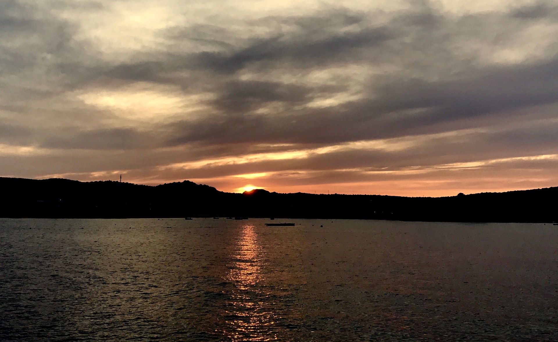 Atardecer entre nubes con reflejo en el mar